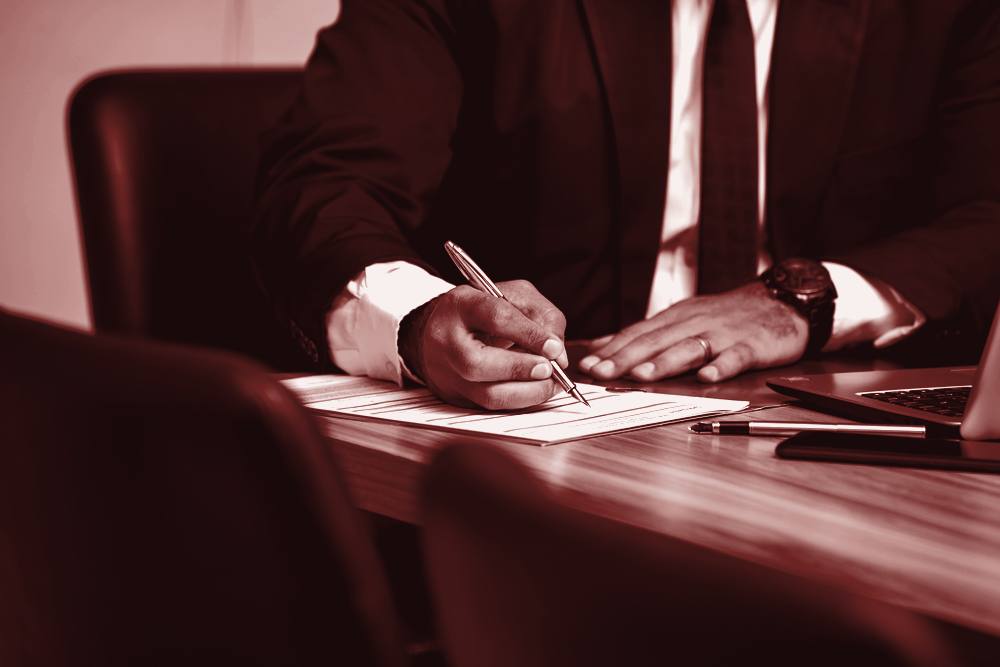 Lawyer signing a document at a meeting table